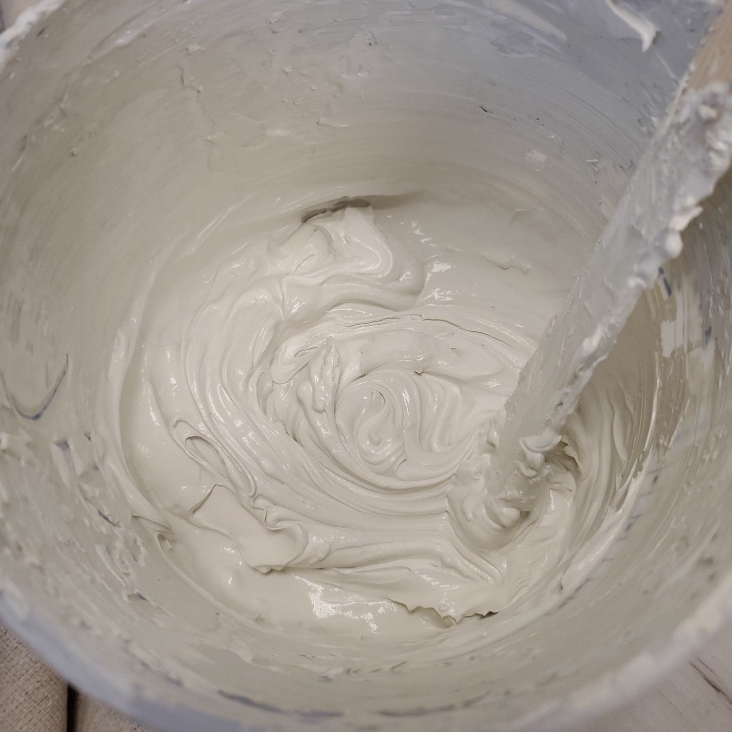 Close-up of drywall mud and neutral paint a container with a paint stick