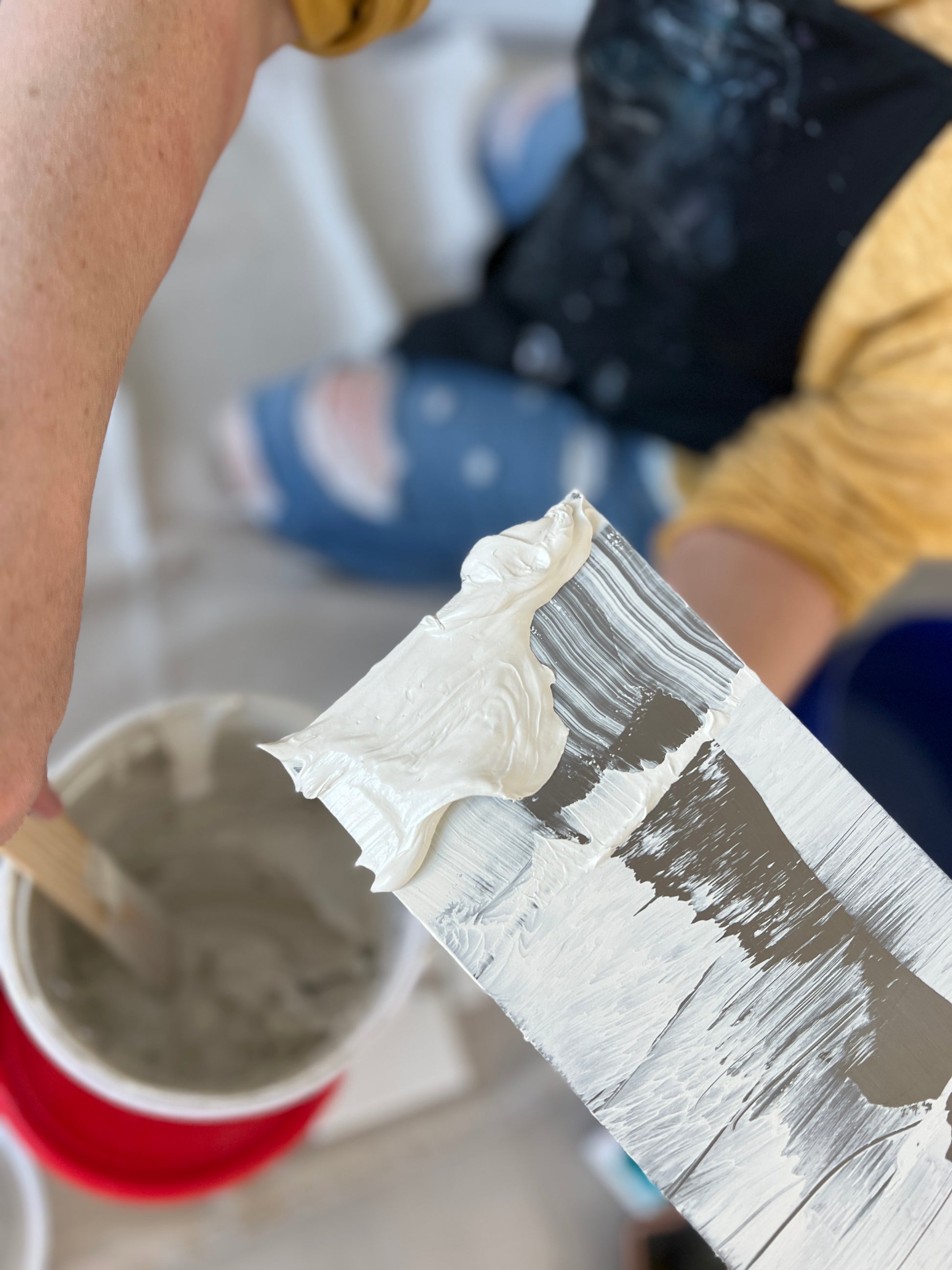Person applying tinted drywall mud to a trowel 