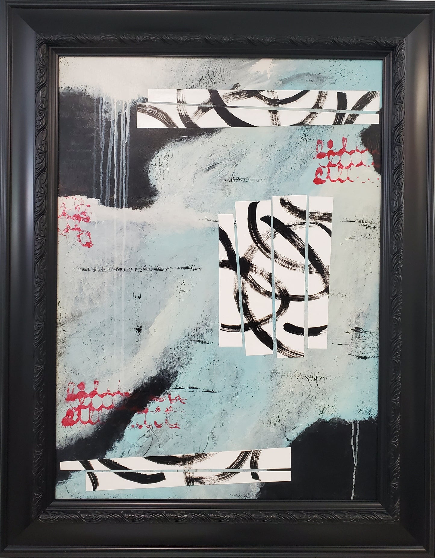Abstract art piece in a black frame on a light gray wall